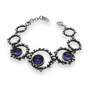 Puede incluir: Un brazalete de plata con tres piedras preciosas púrpuras engastadas en marcos circulares. El brazalete está hecho de pequeñas cuentas y tiene un cierre de langosta.