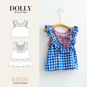 Könnte beinhalten: Ein Schnittmuster für ein Dolly-Kleid und Oberteil von Bebekins, bestehend aus einem ärmellosen blau-weiß karierten Oberteil mit rotem Kirschmuster, gerüschten Schultern und einem rot-weiß karierten Bindeband am Rücken auf einem Holzkleiderbügel.