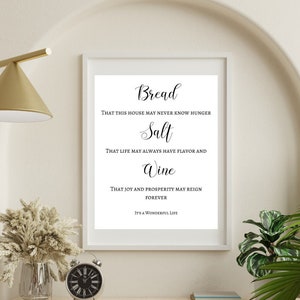 May include: A black and white printable wall art print with the text "Bread that this house may never know hunger, Salt that life may always have flavor and, Wine that joy and prosperity may reign forever, It's a wonderful life."