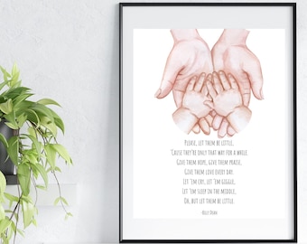 May include: A framed watercolour print showing a parent's hands holding two small hands. The artwork includes a poem with the words "Please, let them be little." The print is in a black frame and displayed on a white shelf.