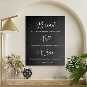 May include: Black chalkboard sign with white text that reads "Bread That this house may never know hunger Salt That life may always have flavor and Wine That joy and prosperity may reign forever It's a wonderful life"