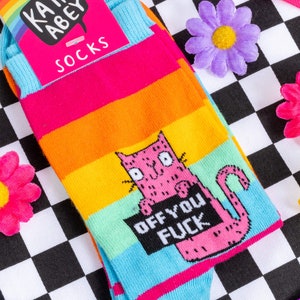 Katie Abey off you fuck socks with pink cat holding a sign. They are rainbow striped and lovely and vibrant.