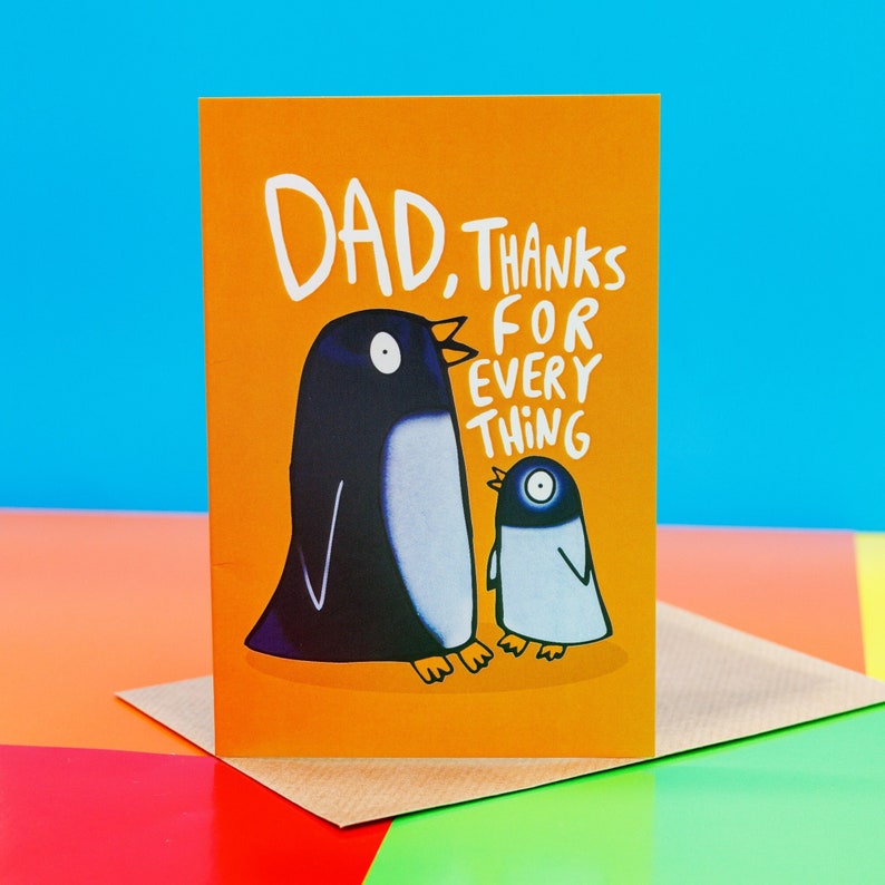 The card is orange with an adult black penguin and baby grey penguin facing each other with text round them reading Dad thanks for everything. Designed by Katie Abey in the UK.
