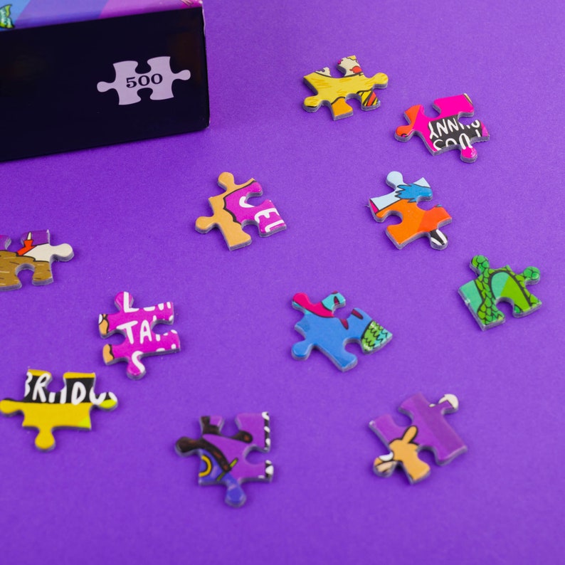 puzzle box with pieces next to it featuring illustrations by Katie Abey on a purple background