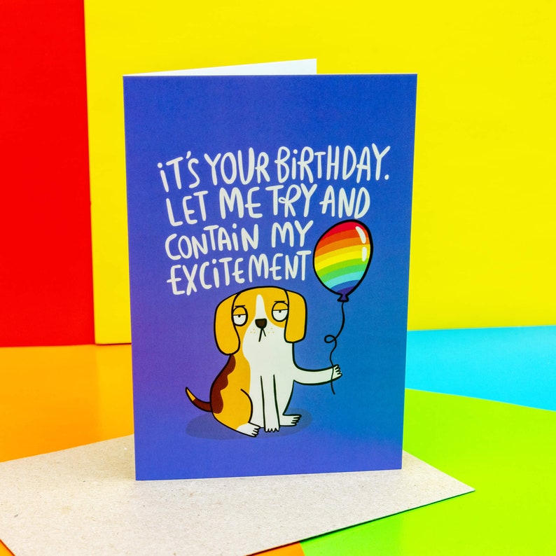 a floppy eared beagle dog on a blue A6 card holding a rainbow balloon looking very unenthusiastic with text saying its your birthday let me try to contain my excitement