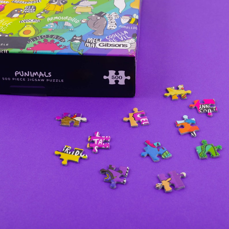 puzzle box with pieces next to it featuring illustrations by Katie Abey on a purple background