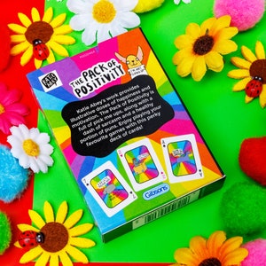 A pack of playing cards with a rainbow smiling on the front illustrated by Katie Abey.
