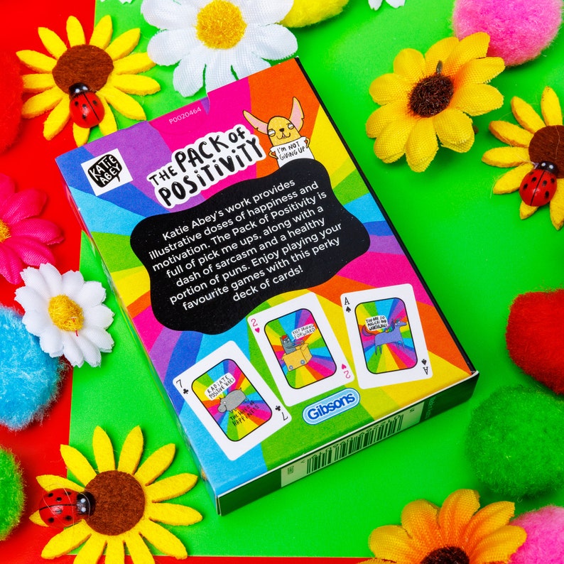 A pack of playing cards with a rainbow smiling on the front illustrated by Katie Abey.