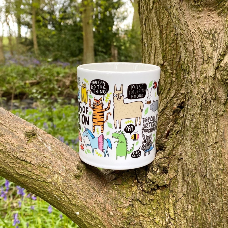 A white ceramic mug with lots of Katie Abey fun illustrations on telling you that you can do it. Text says the Mug of Motivation