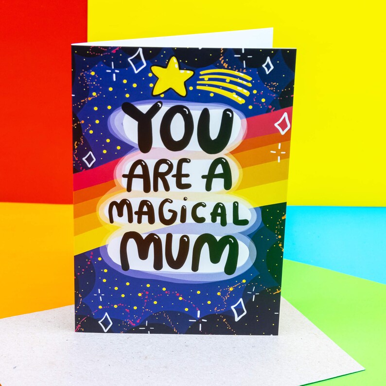 The front cover is a dark blue to black galaxy background with various red, white, yellow stars and sparkles, a red, orange, yellow gradient stripes going across the centre. The text reads You are a magical mum with a yellow shooting star above it.