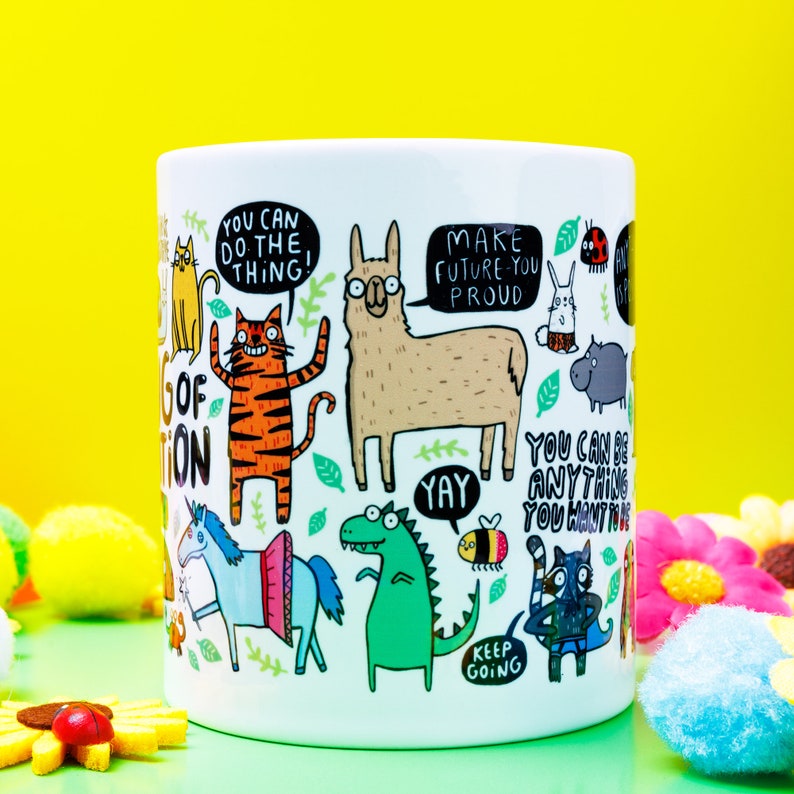 A white ceramic mug with lots of Katie Abey fun illustrations on telling you that you can do it. Text says the Mug of Motivation