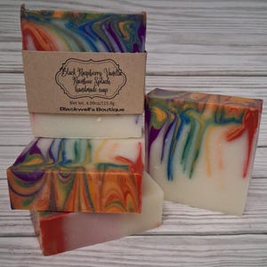 May include: Three rectangular bars of handmade soap with a white base and swirling patterns of orange, purple, blue, and green. A brown paper label on the top bar reads Black Raspberry Vanilla Rainbow Splash handmade soap, Net wt. 4.09oz/115.9g, Blackwell's Boutique.