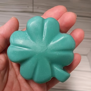 May include: A teal green four-leaf clover shaped soap bar.