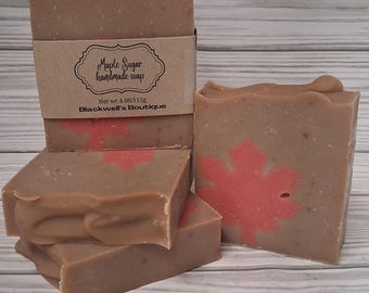 May include: Several bars of handmade soap with a maple sugar scent. The soap is light brown with a red maple leaf design. One bar has a brown paper label that reads "Maple Sugar handmade soap" and "Blackwell's Boutique". Each bar weighs 4.06 oz.