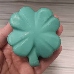 May include: A teal green four-leaf clover shaped soap.