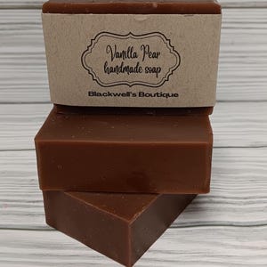 May include: Three bars of brown handmade soap stacked on top of each other. The top bar has a brown paper label with the text "Vanilla Pear handmade soap" and "Blackwell's Boutique".