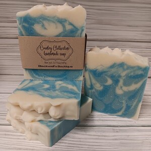 May include: Four bars of handmade soap with a blue and white swirl design. The soap is labeled "Country Clothesline handmade soap" with a net weight of 3.77oz/107g and "Blackwell's Boutique".