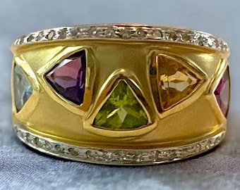 May include: A gold ring with a band of small diamonds and a row of triangular gemstones in various colors, including aquamarine, amethyst, peridot, citrine, and ruby.