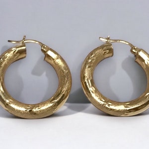 May include: A pair of gold hoop earrings with a textured surface.