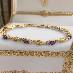 May include: A gold bracelet with a delicate, twisted design features alternating amethyst and diamond accents. The bracelet is displayed on a white background.