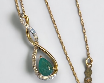 May include: A gold necklace with a pear-shaped emerald gemstone set in a diamond-encrusted infinity symbol pendant.
