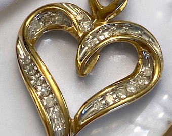 May include: A gold heart-shaped pendant with a smaller heart at the top. The pendant is decorated with small diamonds.