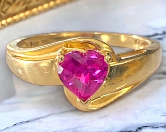 May include: A gold ring with a pink heart-shaped gemstone. The ring has a simple, elegant design.