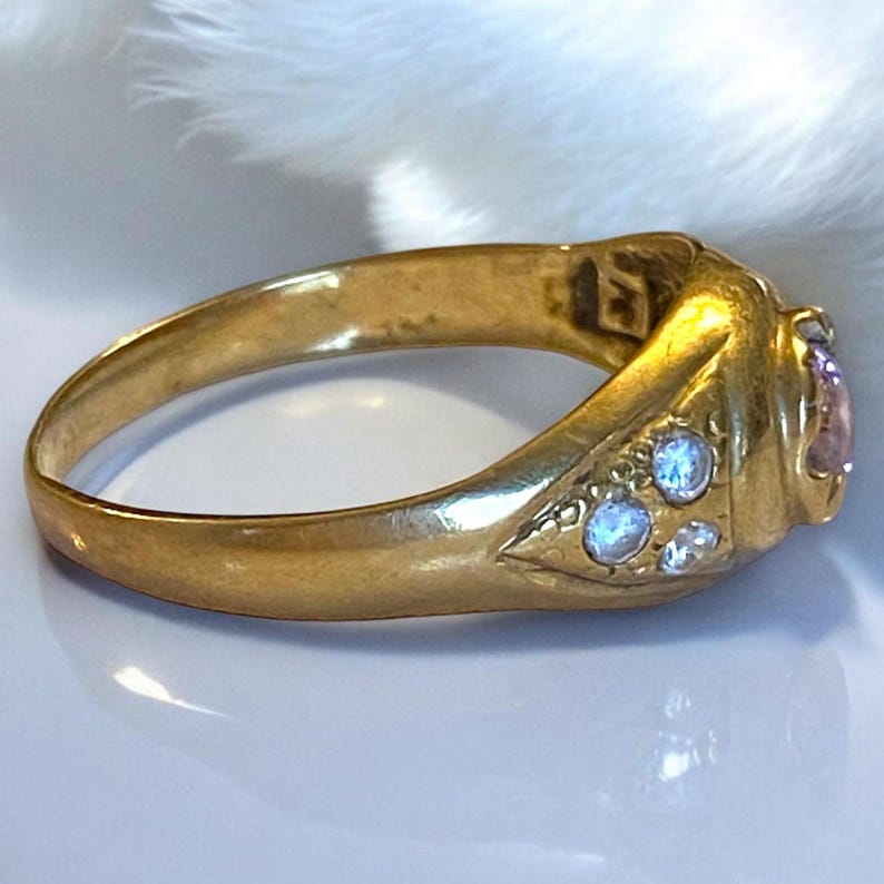 Pu&ograve; includere: Un anello d'oro con una pietra preziosa rosa e pietre preziose pi&ugrave; piccole trasparenti incastonate nella fascia.