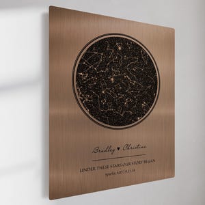 May include: A bronze-colored metal plaque with a circular star map design. The map is black with white star details. The plaque includes the names "Bradley" and "Christine" with the text "UNDER THESE STARS OUR STORY BEGAN" and the location "Sparks, MD | 9.21.18".