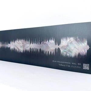 May include: A rectangular black metal plaque featuring a horizontal iridescent sound wave graphic. The text reads "OUR SOUNDTRACK: VOL. 30", "William & Erika 5.25.1996", and includes a small square QR code printed in the bottom right corner.