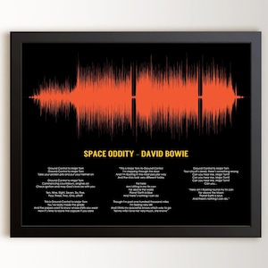 May include: A framed wall art print featuring a bright orange sound wave graphic on a black background. Below the graphic, the text reads SPACE ODDITY - DAVID BOWIE, followed by the complete lyrics to the song printed in white text.