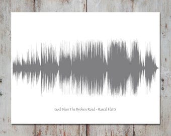 May include: A rectangular white print featuring a centered grey sound wave graphic. Below the sound wave, the text reads God Bless The Broken Road - Rascal Flatts in a simple black font. The design is presented on a clean white background.