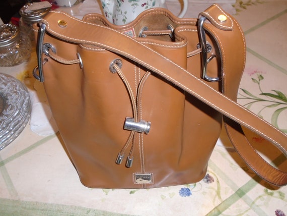 Dooney and Bourke Purse Drawstring Closure w Locking Slide Top Handle w Metal Saddle Hardware Attachment Metal Tips Metal Plated Logo