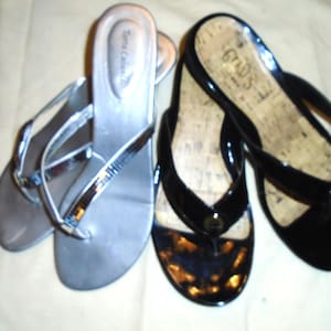 Peut inclure: Deux paires de sandales pour femmes. Une paire est argentée avec une bride en lanière et un petit talon compensé. L'autre paire est noire avec une semelle intérieure en liège et une bride en lanière.