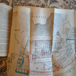 May include: A black and white map of the Acropolis in Athens, Greece. The map shows the location of the Museum, the Temple of Athena Nike, the Propylaea, the Erechtheum, and the Parthenon. The map is labeled "ACROPOLIS" in large letters.