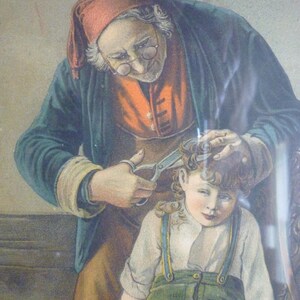 May include: A vintage framed print showing a barber cutting a young boy's hair. The barber, in a red cap and glasses, uses scissors. The boy wears a white shirt, green trousers, and braces. The artwork has a warm colour palette.
