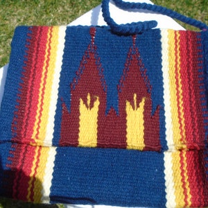 Bolso bohemio tejido, de lana. Rayas multicolores y solapa frontal tipo catedral. Bolso de hombro azul, dorado, óxido y rojo. Creo que es de lana.