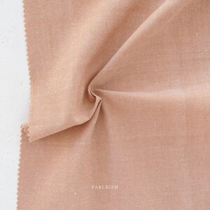 May include: Close-up of a light brown fabric with a subtle texture. The fabric is folded and has a slight sheen.