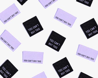 May include: A collection of purple and black fabric labels with the text "You can't buy this" printed on them. The labels are arranged in a random pattern on a white background.