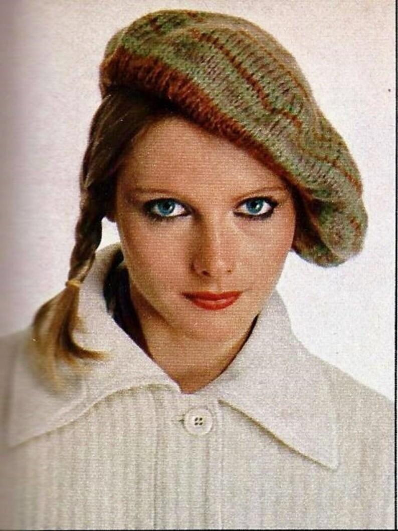 Peut inclure: Une femme aux longs cheveux blonds porte un pull blanc &agrave; col et &agrave; bouton. Elle porte &eacute;galement un b&eacute;ret en tricot vert et marron.