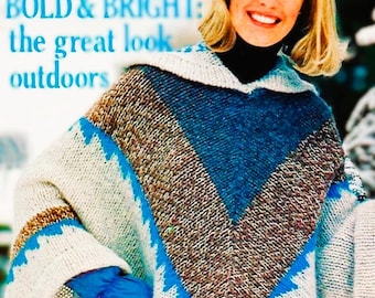 Op de afbeelding: Een gebreide poncho met capuchon, met een colorblock-ontwerp in wit, bruin en blauw. De poncho heeft een zigzagpatroon in blauw. De tekst "BOLD & BRIGHT: the great look outdoors" is zichtbaar.