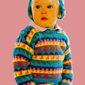 May include: A child wearing a colourful striped jumper and matching hat. The jumper has a geometric pattern and is made of a soft, knitted fabric.