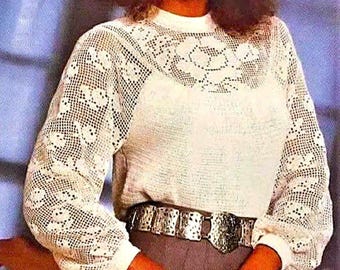 Pode incluir: Um top branco de crochê com um design floral. O top tem mangas compridas e um decote redondo. A modelo está usando um cinto prateado com uma fivela grande.