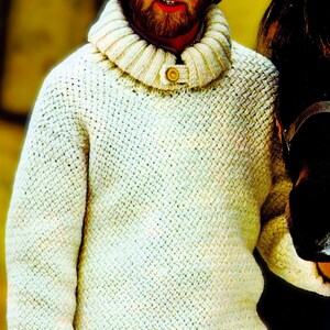 May include: Cream-colored, textured knit sweater with a high, folded collar and a single button closure. The sweater has a thick, woven appearance and long sleeves. The overall style suggests a warm, rustic aesthetic, suitable for cold weather.