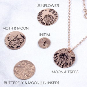 K&ouml;nnte beinhalten: Ein Set aus ros&eacute;goldenen Kettenanh&auml;ngern mit verschiedenen Designs, darunter eine Sonnenblume mit dem Wort "happiness", ein Mond und eine Motte, ein Schmetterling und ein Mond, ein Mond und B&auml;ume sowie ein Initial "A".