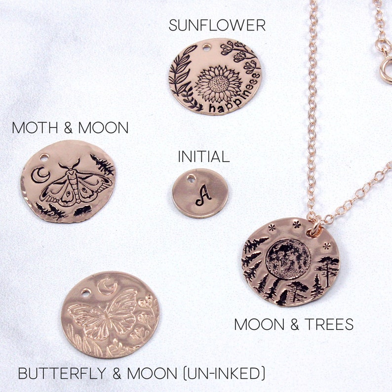 K&ouml;nnte beinhalten: Ein Set aus ros&eacute;goldenen Kettenanh&auml;ngern mit verschiedenen Designs, darunter eine Sonnenblume mit dem Wort "happiness", ein Mond und eine Motte, ein Schmetterling und ein Mond, ein Mond und B&auml;ume sowie ein Initial "A".