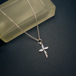 May include: A silver chain necklace with a delicate, twisted cross pendant.