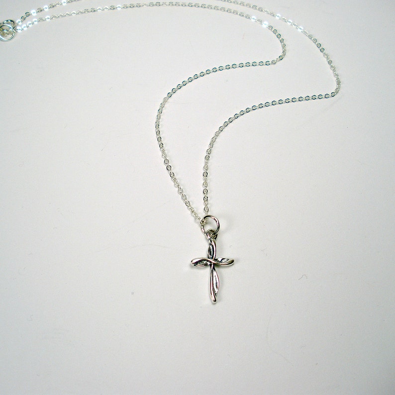 May include: A silver chain necklace with a small, twisted silver cross pendant.