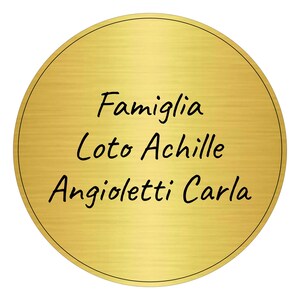 May include: A gold round plaque with the text "Famiglia Loto Achille Angioletti Carla" written in black.