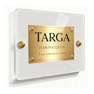 May include: A rectangular, clear acrylic sign with a gold-colored metal plate. The plate is secured with four gold-colored screws and features the word "TARGA" in bold black letters. Below, the text "PERSONALIZZATA" and "Il tuo testo inciso a laser" are also visible.
